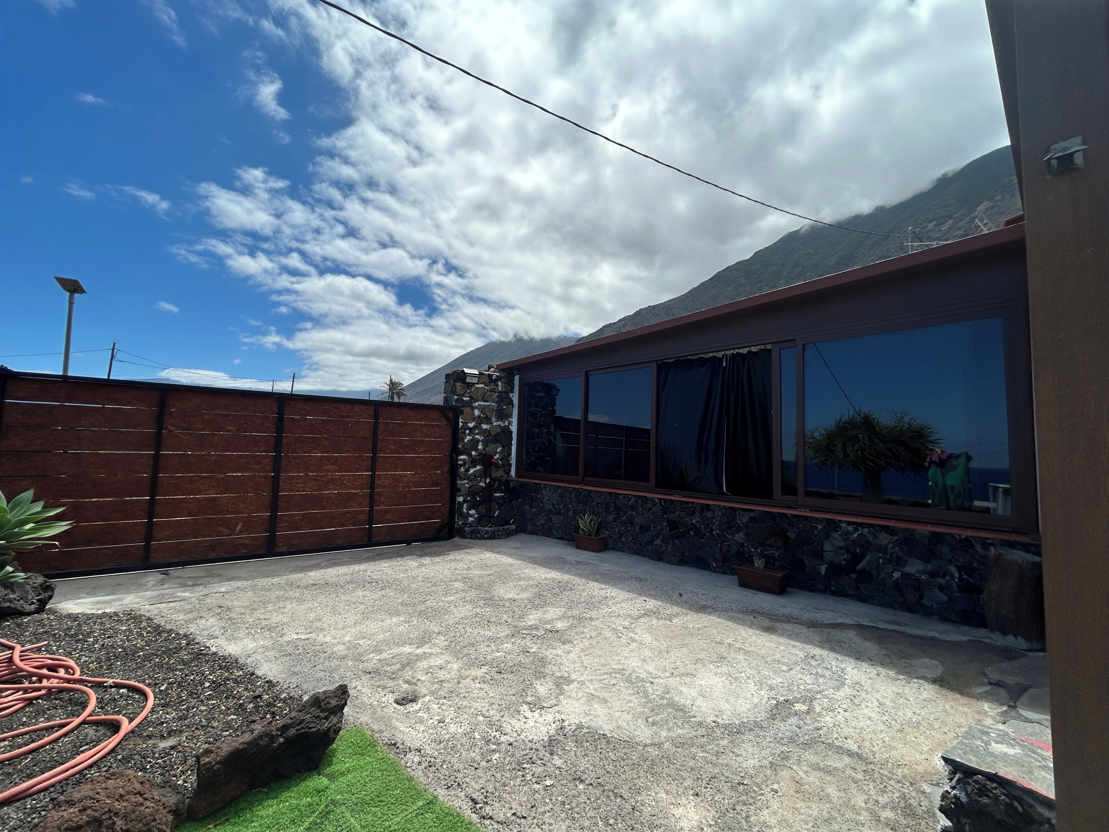 Une terrasse en béton avec une clôture en bois, un mur en pierre et une grande fenêtre.