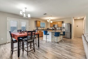 A modern kitchen with a central island, bar stools, and a dining area with a table and chairs. - Adorable 3-bedroom house with AC in charming Venus (Venus)