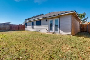 Ein bungalow mit Garage, einem eingezäunten Garten und blauem Himmel.