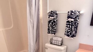 Een badkamer met douche, toilet en wastafel.