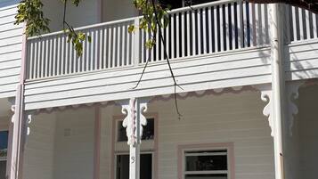 A two-story house with a balcony, a porch with a railing, and a small window.