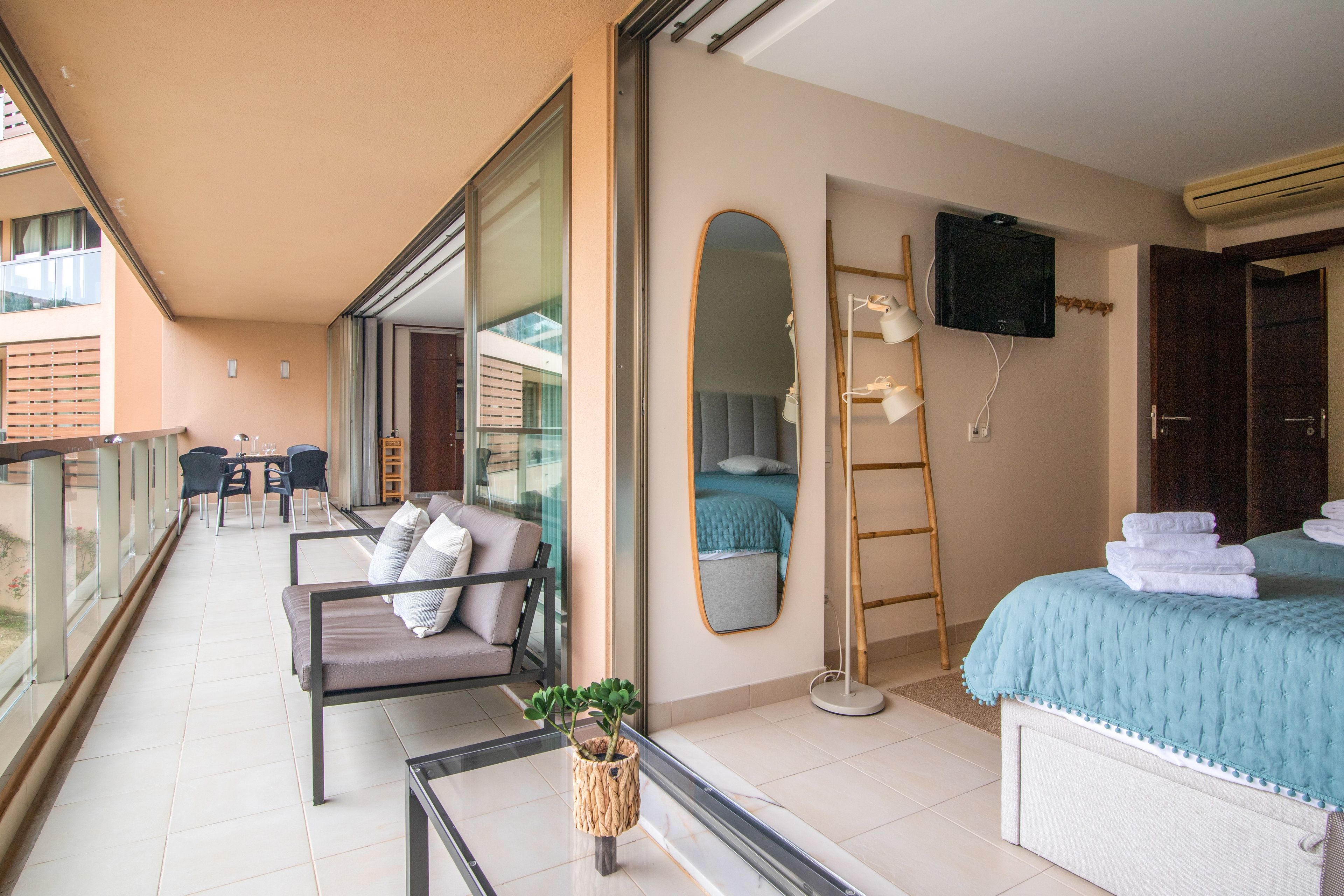 Ein Balkon mit einer Couch, einem kleinen Tisch mit einer Pflanze und Blick ins Freie.
