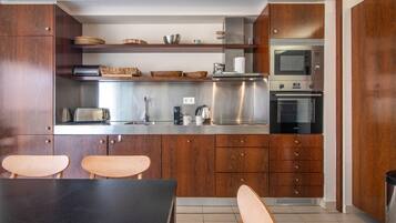 Eine moderne Küche mit Holzausstattung, Edelstahlgeräten und einem Essbereich mit zwei Stühlen.