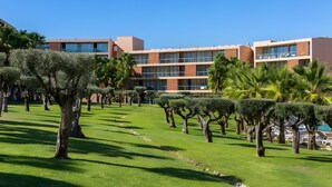 Un hôtel moderne à plusieurs étages, doté d’une pelouse bien entretenue et d’une grande variété d’arbres.