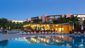 Un espace aménagé au bord de la piscine, avec des chaises longues et un restaurant décoré de guirlandes lumineuses.