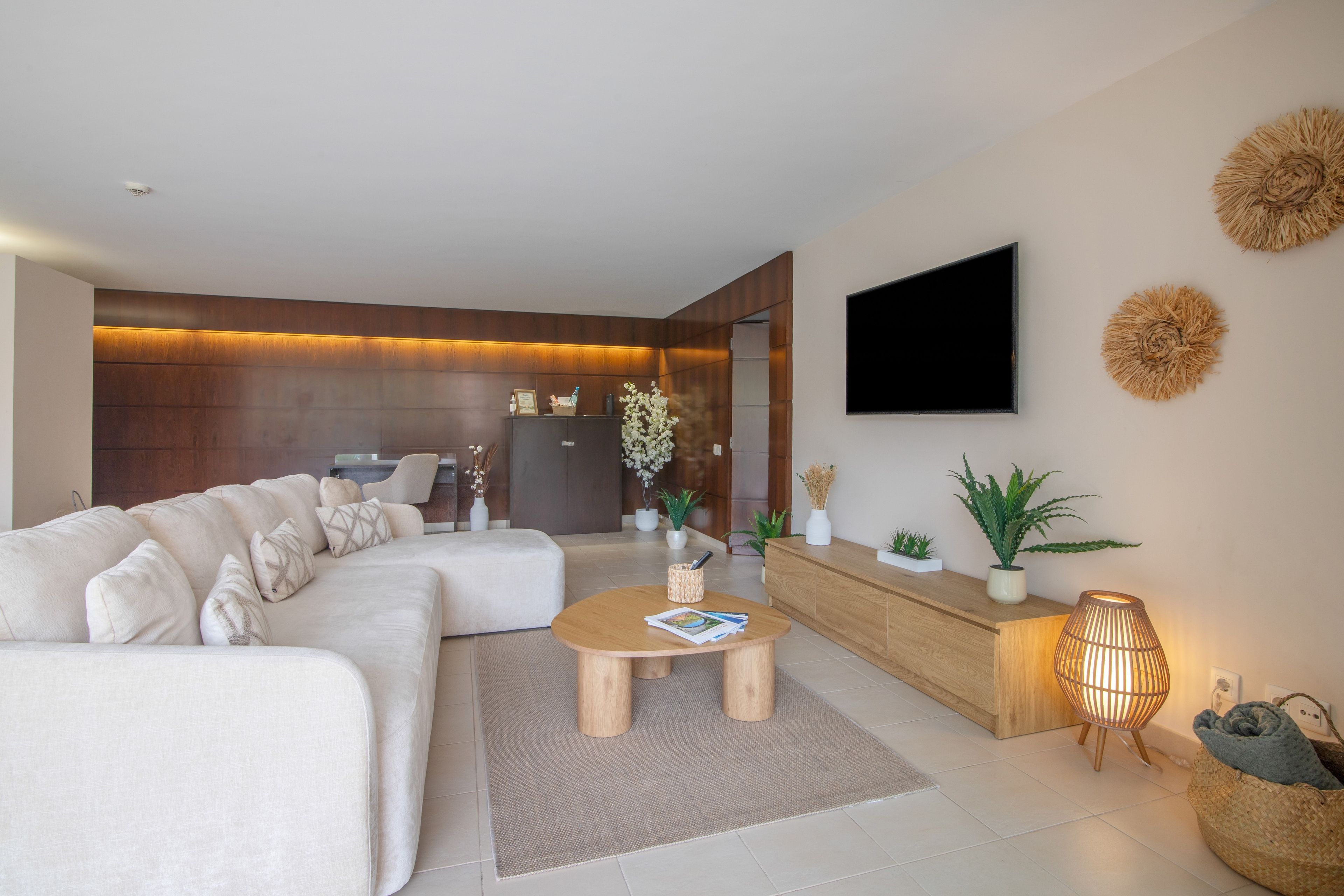 Ein modernes Wohnzimmer mit Ecksofa, Couchtisch, Flachbildfernseher an der Wand und einer Rezeption.