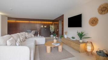 Ein modernes Wohnzimmer mit Ecksofa, Couchtisch, Flachbildfernseher an der Wand und einer Rezeption.