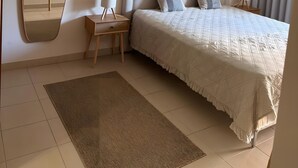 Une chambre à coucher avec un lit, des tables de chevet, un miroir et une fenêtre avec des rideaux.