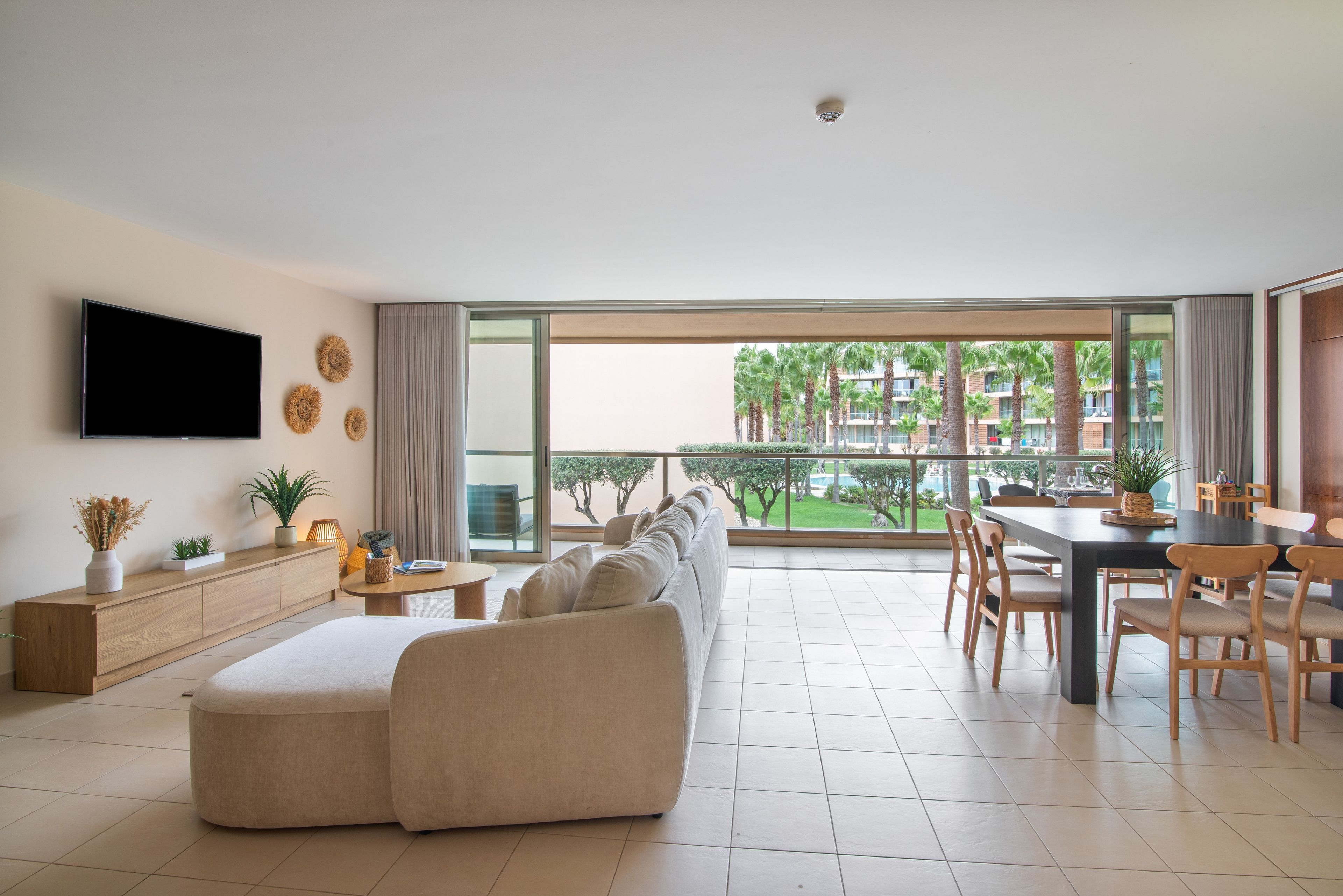 A modern living room with a sofa, TV, and dining area with chairs and a table.