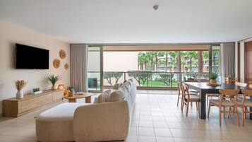 A modern living room with a sofa, TV, and dining area with chairs and a table.
