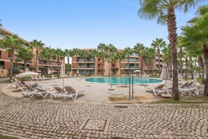 A resort pool area with lounge chairs and palm trees. - Apartment 'Guiga Living - Herdade Dos Salgados' with Wi-Fi and Air Conditioning (Guia)