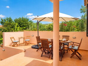An outdoor patio with a table and chairs, surrounded by a low wall and greenery. - Private Methoni 3 Bedroom Villa Walk to Castle and Beach. (methoni)