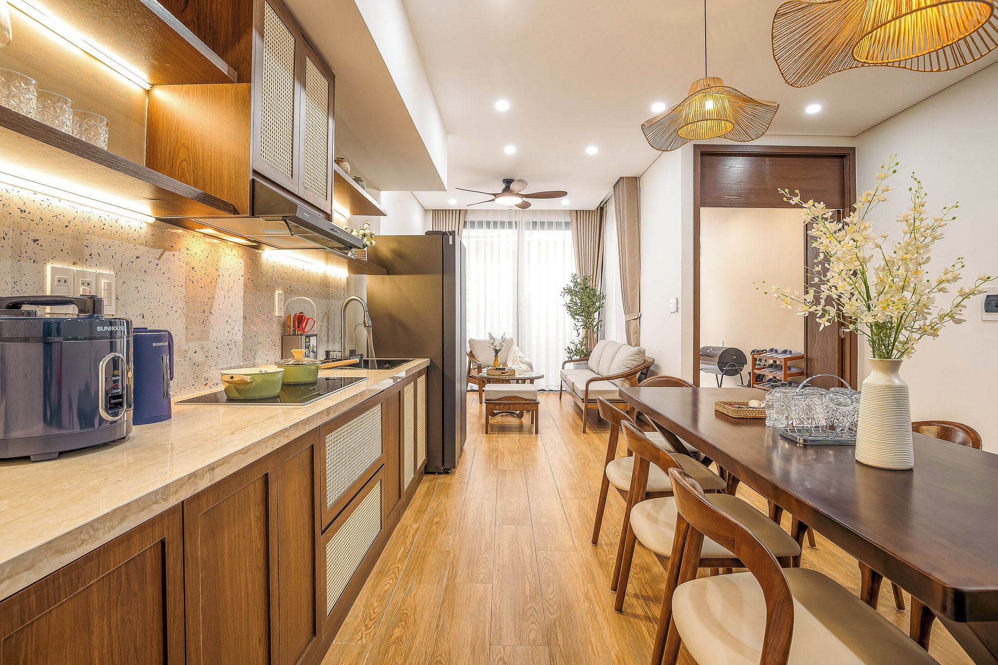A modern kitchen with a built-in stove, a dining area with wooden chairs, and a ceiling fan.