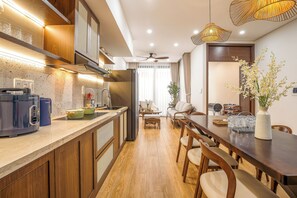 A modern kitchen with a built-in stove, a dining area with wooden chairs, and a ceiling fan. - The Querencia Arena Private Pool villa and Free Pick up (Đà Nẵng)