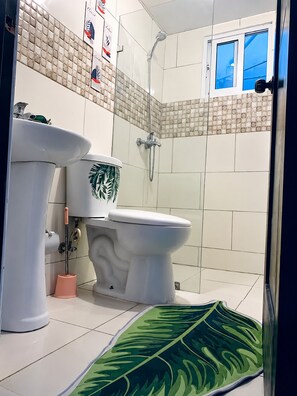 Een badkamer met toilet, hygiëneschuimer en douche.