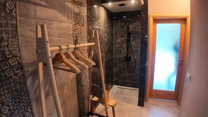 A bathroom with a wooden towel rack, a shower area, and a patterned wall. - Vrbo Property (Gornji Orašac)