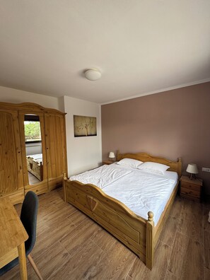A bedroom with a wooden bed, a desk, a chair, a nightstand with a lamp, and a mirror. - Vrbo Property (Gornji Orašac)