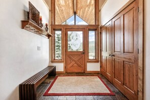 A hallway with a wooden door, a bench, and a rug. - Spacious Mountain Home w/ Panoramic Mount Sopris Views (Glenwood Springs)