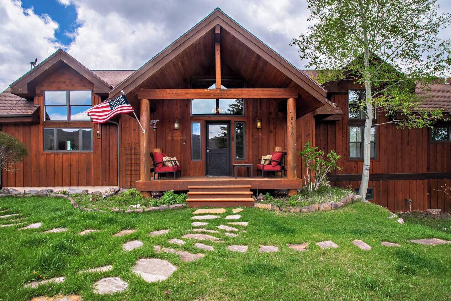 Eine Holzhütte mit Veranda, zwei Stühlen und einer amerikanischen Flagge.