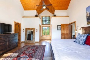A bedroom with a large bed, wooden ceiling, a television, a fireplace, and a view of the outdoors. - Spacious Mountain Home w/ Panoramic Mount Sopris Views (Glenwood Springs)