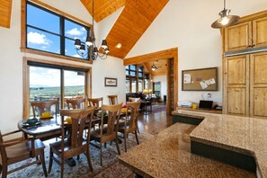 A spacious kitchen with wooden cabinets, a granite countertop, and a dining area with wooden chairs and a table. - Spacious Mountain Home w/ Panoramic Mount Sopris Views (Glenwood Springs)