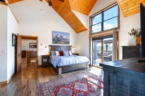 Una camera da letto con un letto grande, un soffitto in legno, un'ampia finestra e vista sull'esterno.