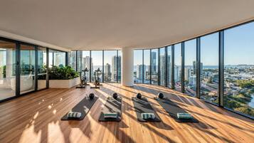 A spacious room with large windows, exercise equipment, and a view of a cityscape.