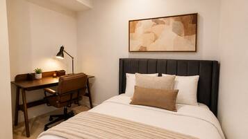 A bedroom with a bed, a desk, and a chair.
