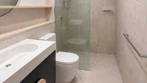 Une salle de bain moderne avec une douche à parois de verre, un lavabo blanc et des toilettes.