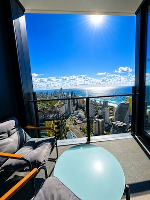 A balcony with a city view, a table, and a chair. - Horizon Haven - Panoramic Ocean Views (Broadbeach)