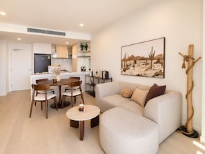 A modern living room with a sofa, coffee table, and dining area with chairs. - Horizon Haven - Panoramic Ocean Views (Broadbeach)