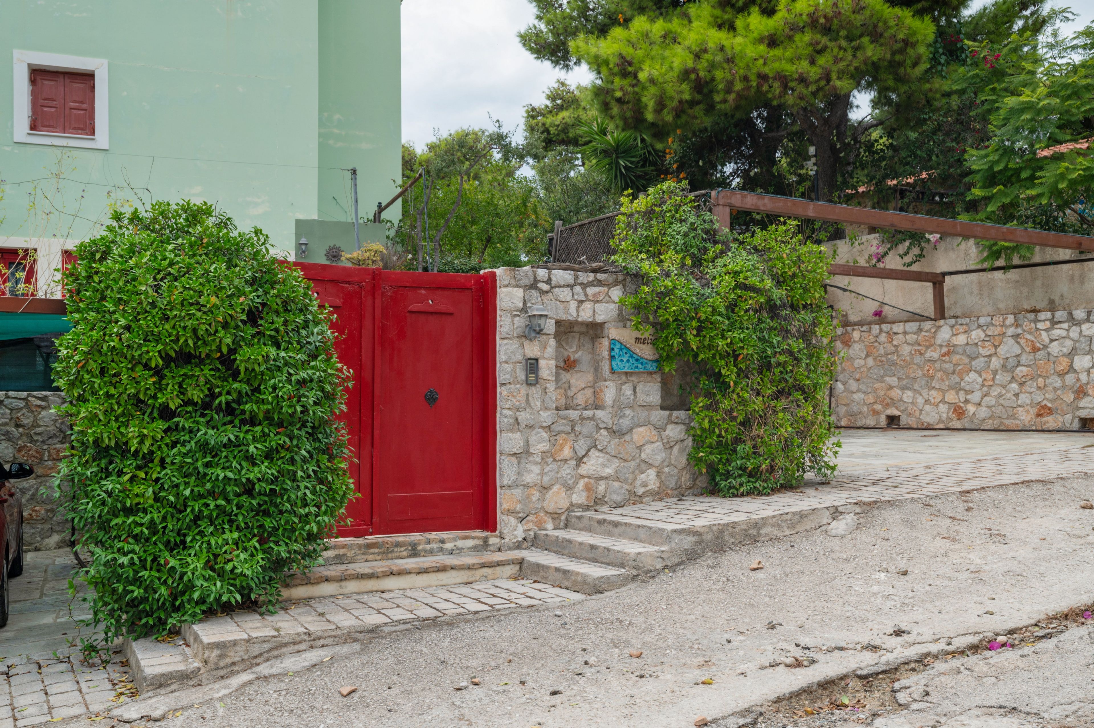 Une porte rouge, un mur de pierre et des marches menant à un bâtiment.