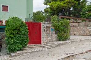Una porta vermella amb una paret de pedra i escales que condueixen a un edifici.