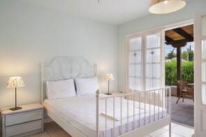 Ein Schlafzimmer mit einem Bett, Nachttischen, Lampen und Blick ins Freie.