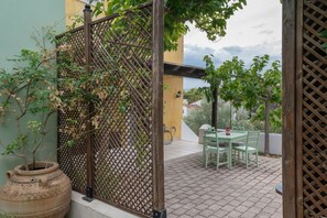 Eine Terrasse mit Tisch und Stühlen, einem Blumentopf und einem Spalier.