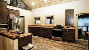 A spacious kitchen with wooden flooring, a built-in oven, and a large island with a sink.