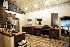 A spacious kitchen with wooden flooring, a built-in oven, and a large island with a sink.