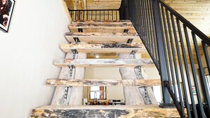 A wooden staircase with a black railing and a ceiling fan.