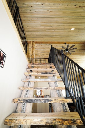 A wooden staircase with a black railing and a ceiling fan.