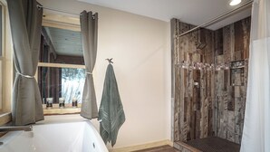 Een badkamer met een douche, een bad en een raam met gordijnen.