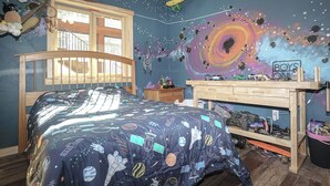 A bedroom with a bed, a desk, and a wall mural.