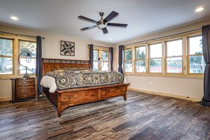 A bedroom with a wooden bed, a ceiling fan, and large windows. - A remote private mountain retreat complete with a 4WD 4 seat side by side (Bridger)