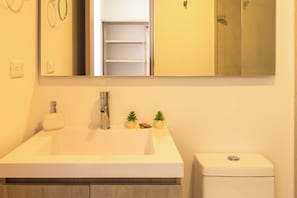 A bathroom with a white sink, a mirror, and a toilet. There are two small potted plants on the sink counter. - Oceani Towers Cielo Mar · Rooftop, beach 5 min (Cartagena de Indias)
