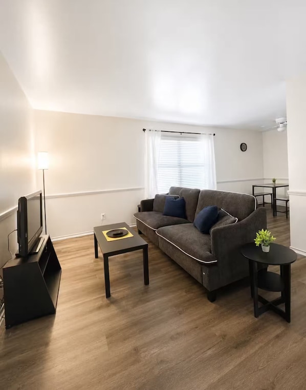 A modern living room with a sofa, coffee table, and a TV stand.