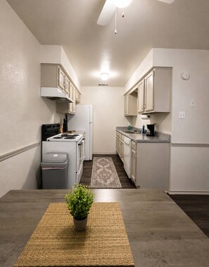 A compact kitchen with white cabinets, a stove, a refrigerator, and a sink.