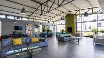 Un hall espacioso con mobiliario moderno, ventanas amplias y un techo alto con vigas a la vista.