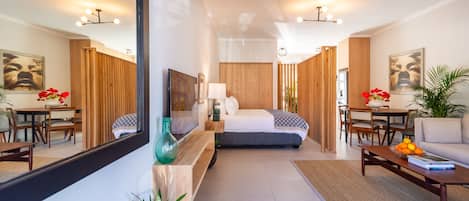 A modern hotel room with a large bed, a sitting area with a coffee table, a dining table, and a large mirror.