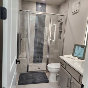 Uma casa de banho moderna com chuveiro em cabine de vidro, sanita e lavatório.