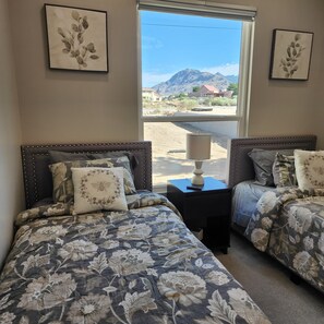 Un dormitorio con dos camas, cada una con ropa de cama floral y cabeceros a juego, una mesita de noche con lámpara y cuadros en las paredes.