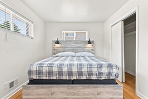 A bedroom with a bed, a window with blinds, a wardrobe, and a wall-mounted light fixture.